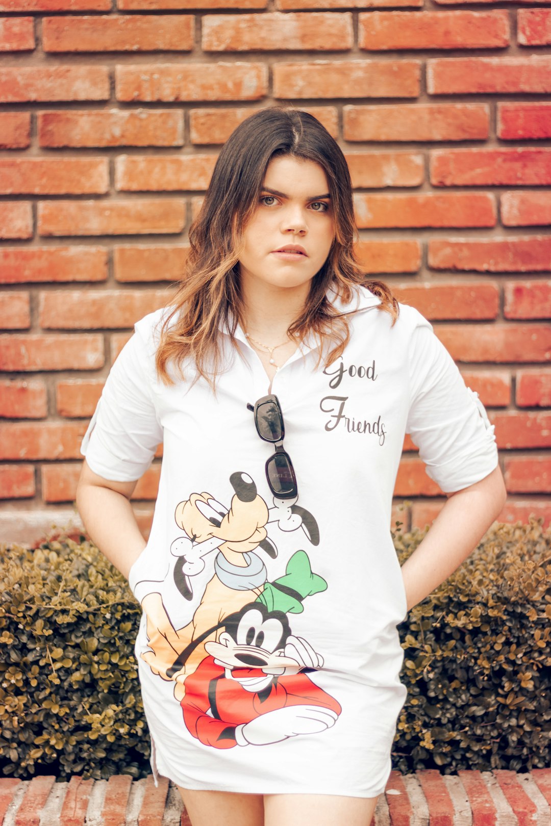 woman in white crew neck t-shirt standing beside brown brick wall