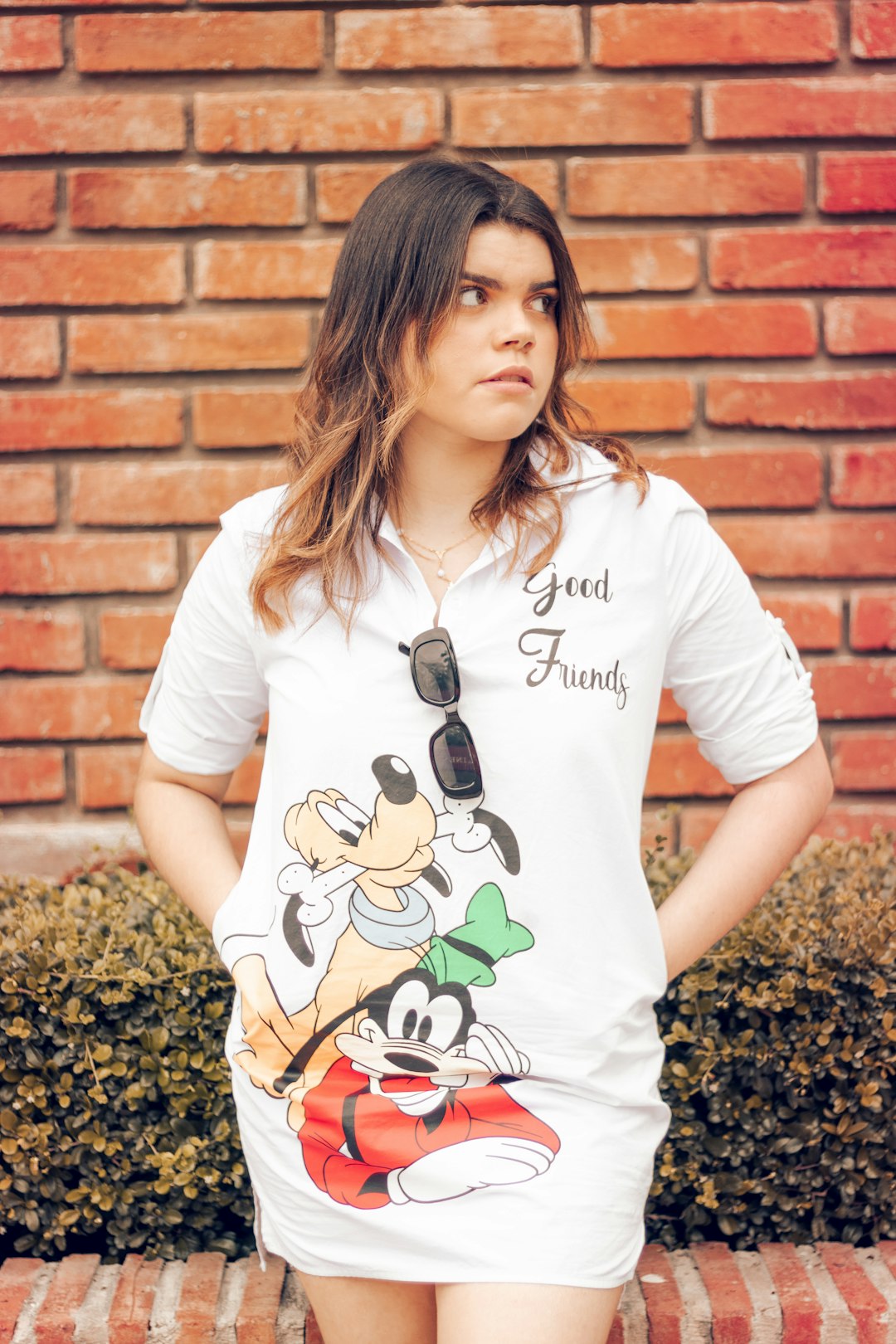 woman in white crew neck t-shirt standing beside brown brick wall