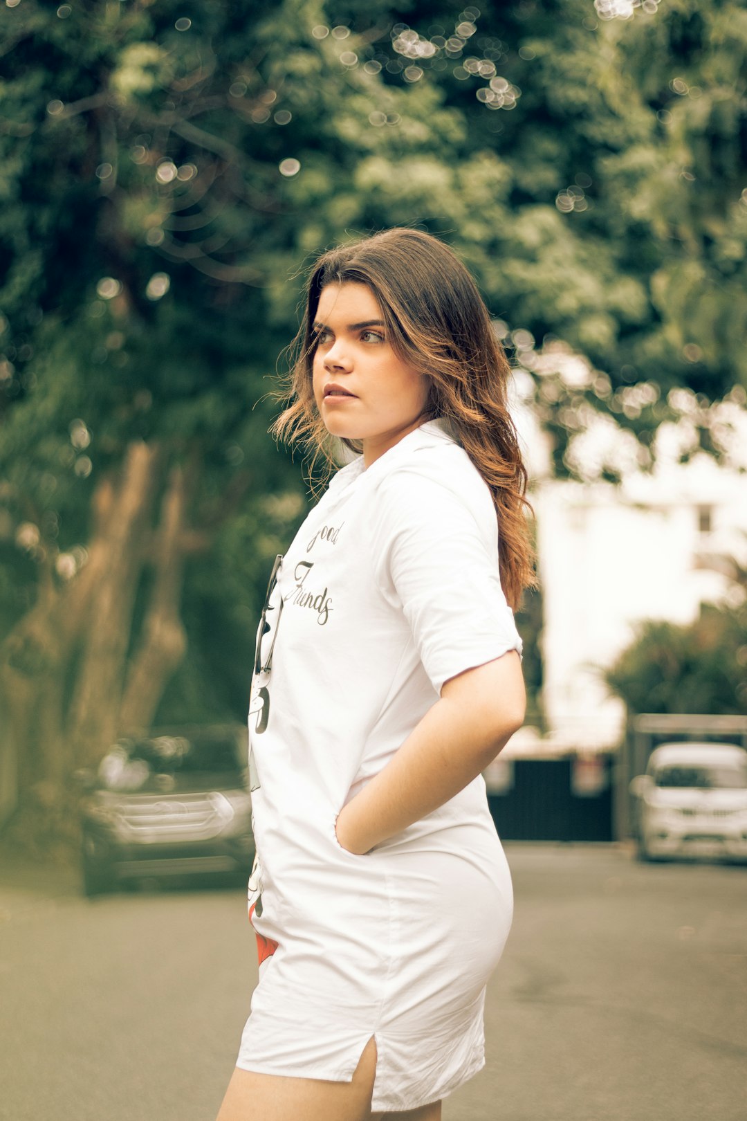 woman in white crew neck t-shirt standing near green trees during daytime