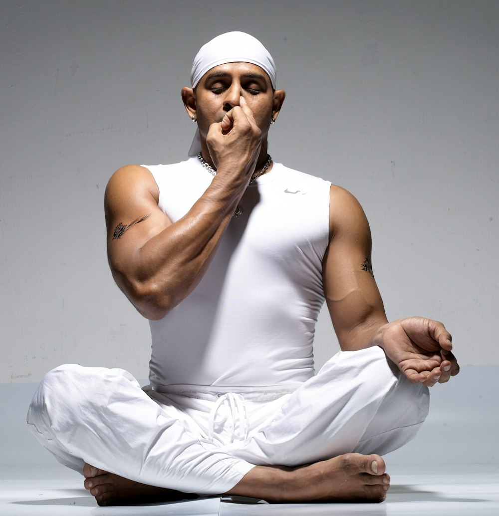 man in white tank top and white pants sitting on floor