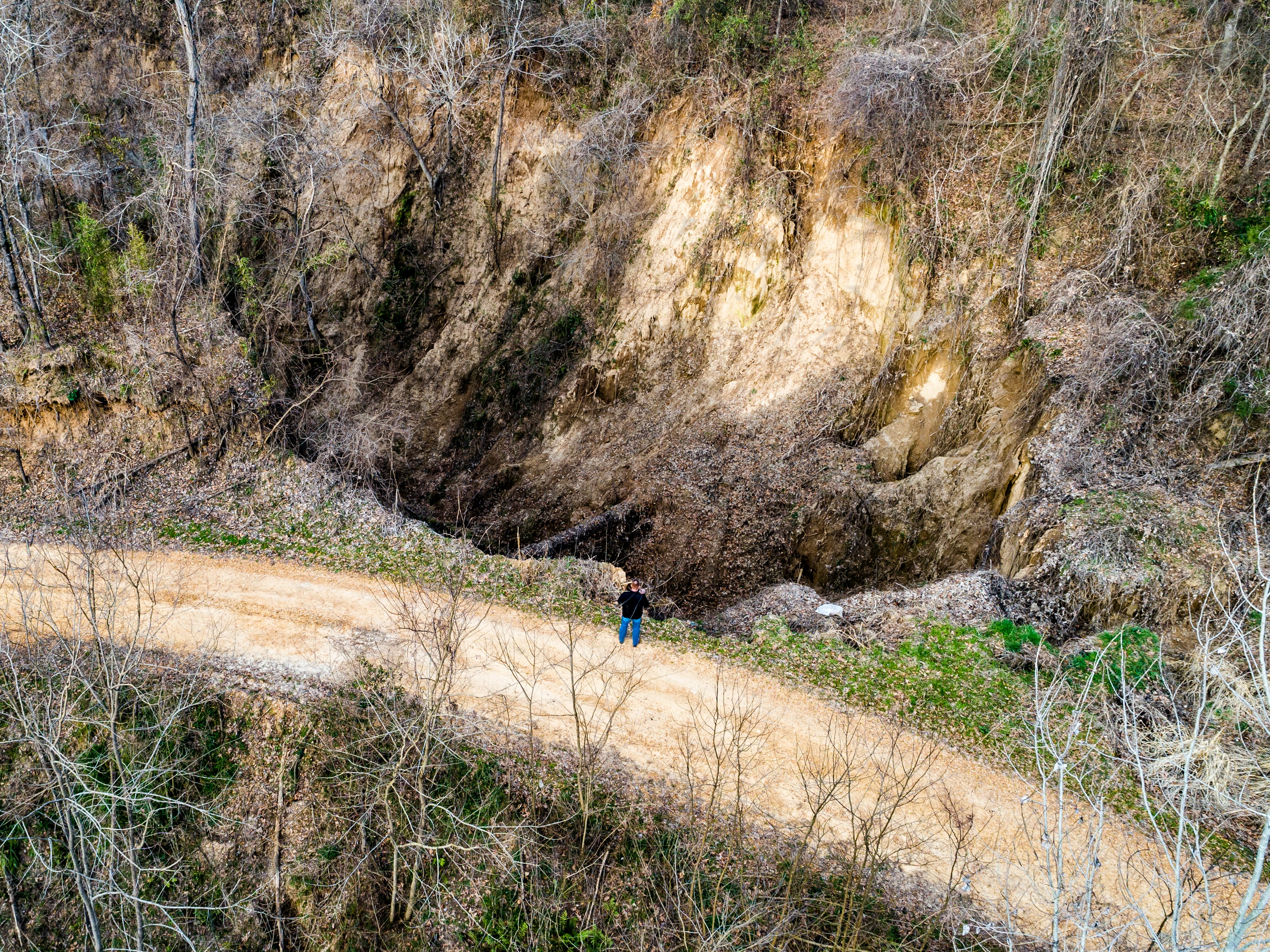 person in blue jacket walking on dirt road between brown rocky mountain during daytime