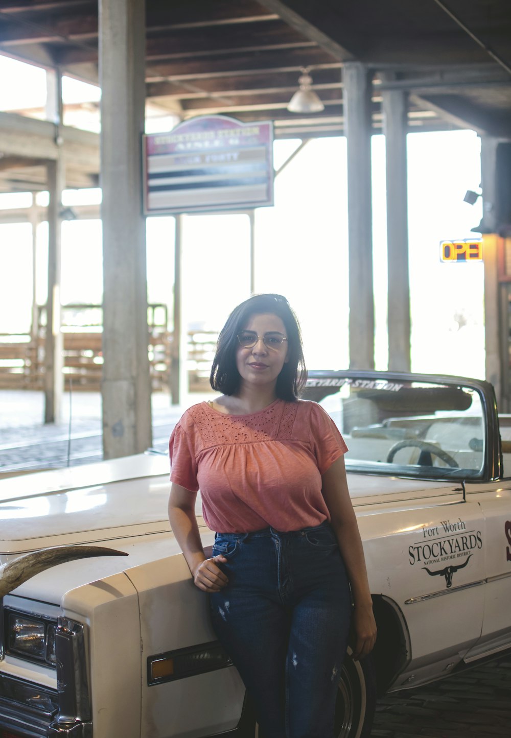 woman in red shirt and blue denim jeans sitting on brown car