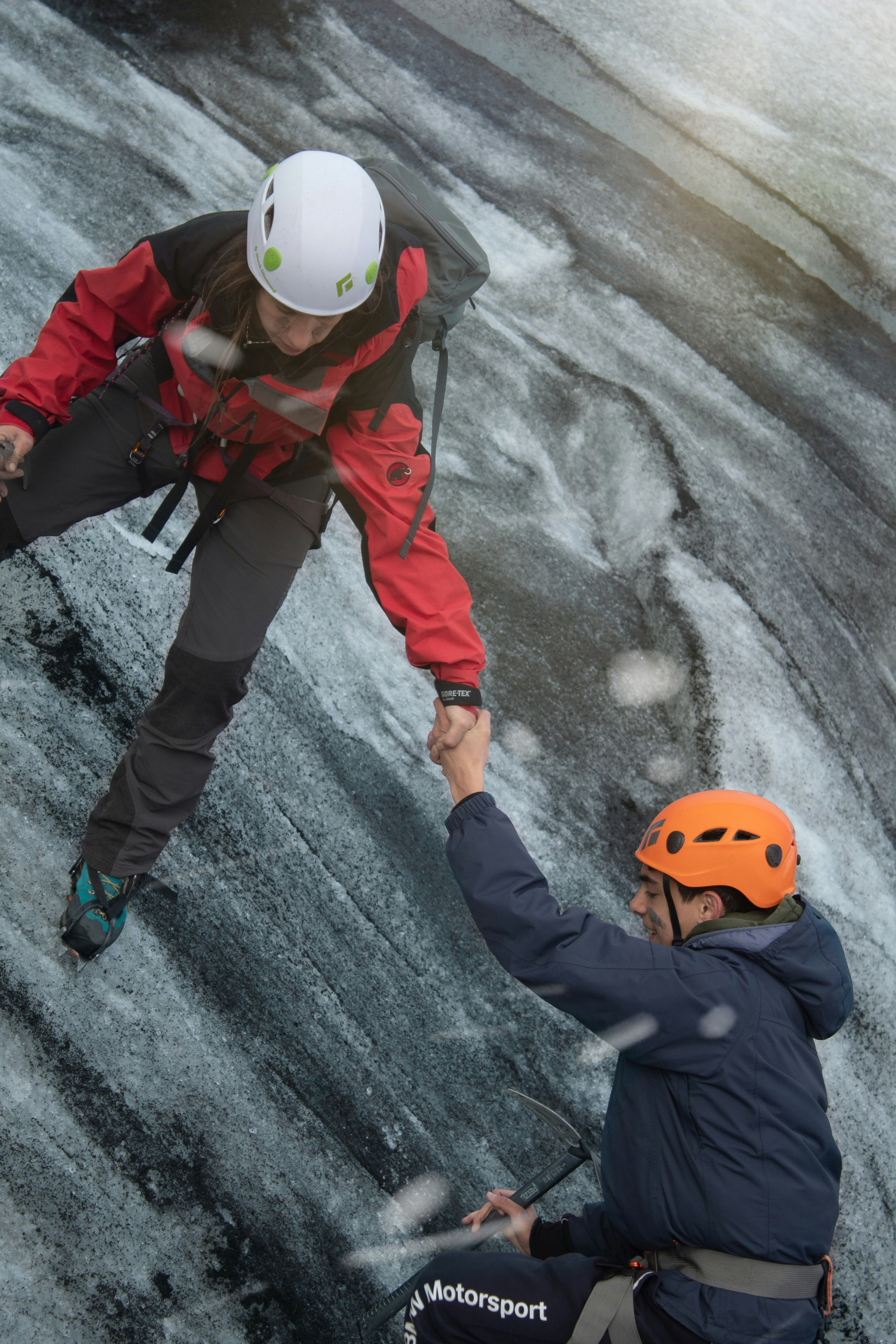 child in red jacket and white helmet standing on gray rock