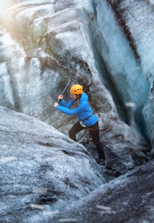 man in blue t-shirt climbing on gray rock
