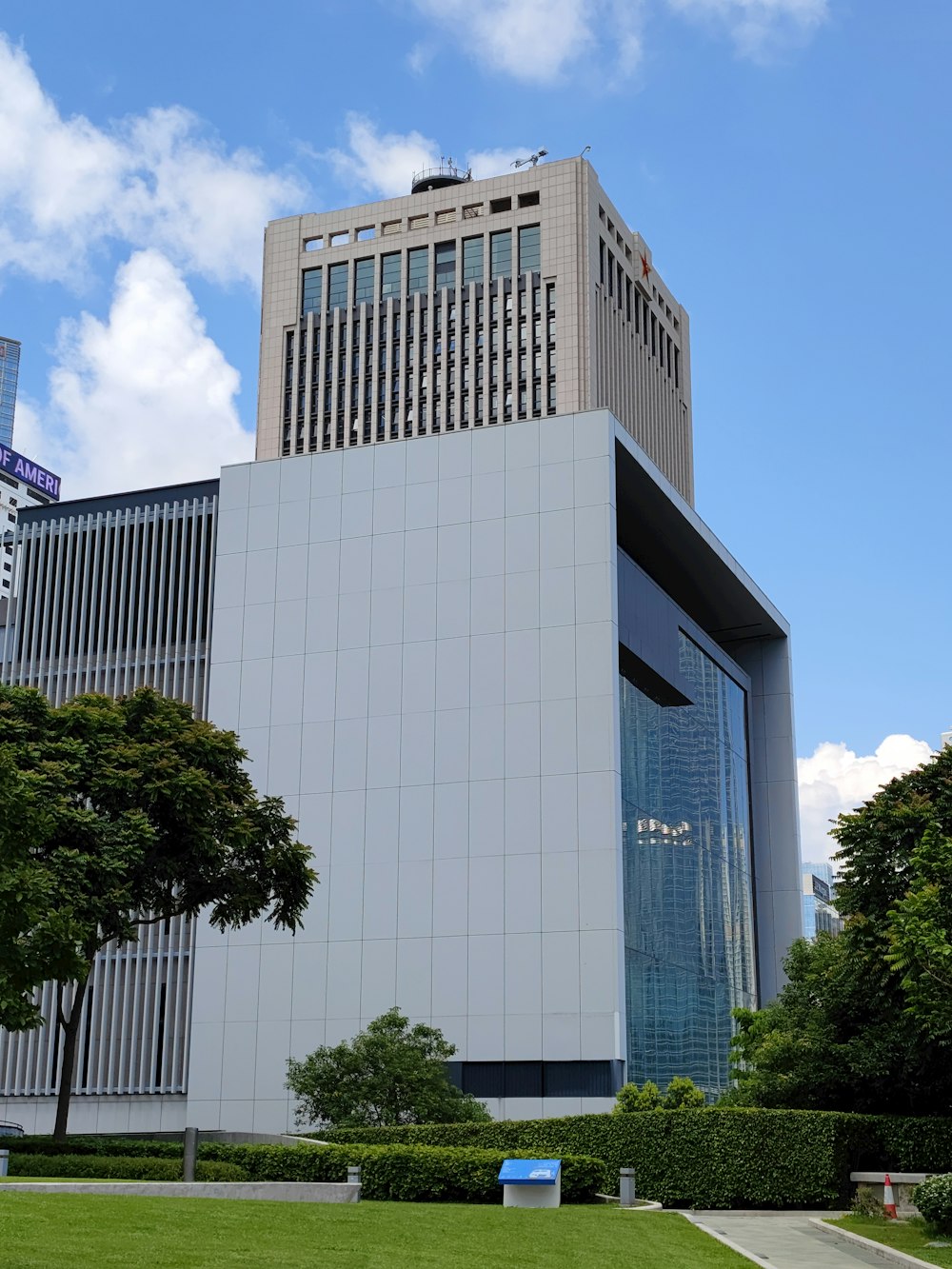 Edificio de hormigón blanco cerca de árboles verdes bajo el cielo azul durante el día