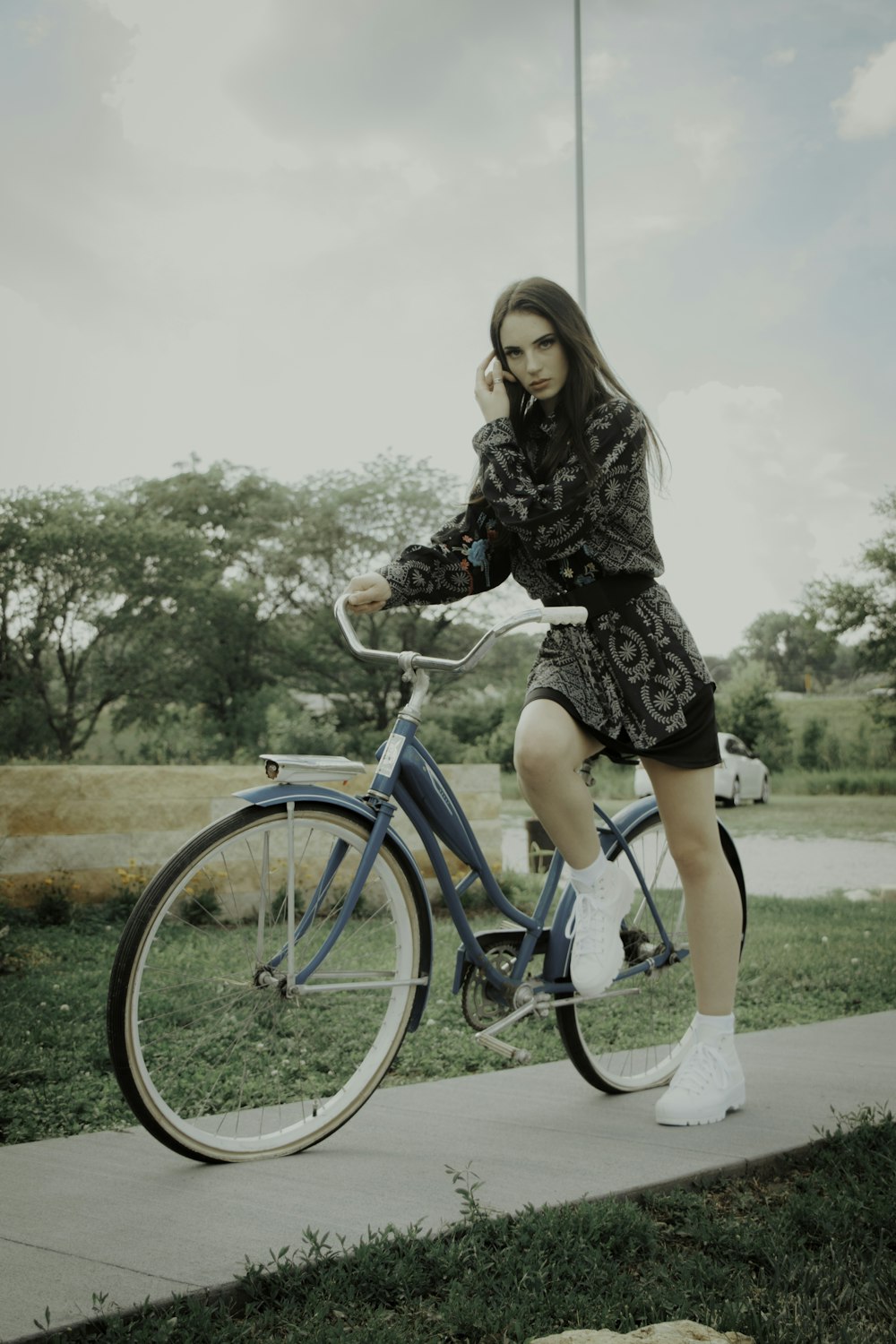 woman in black dress riding blue bicycle during daytime