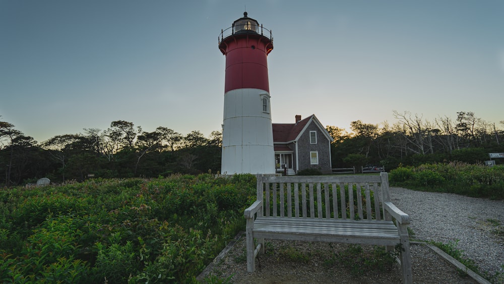 white and red lighthouse near green trees under blue sky during daytime