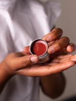 person holding red and silver round container