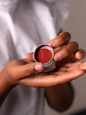 person holding red and silver round container