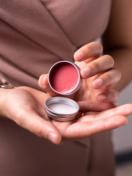 person holding silver and red round case