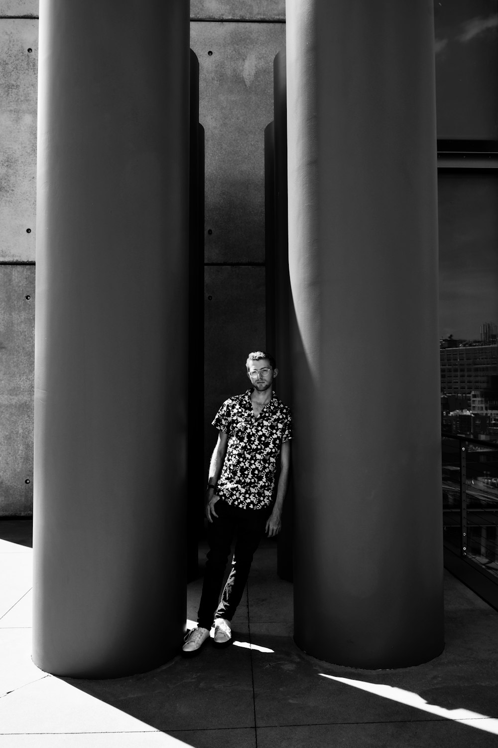 grayscale photo of man in black and white polka dot shirt and black pants standing beside