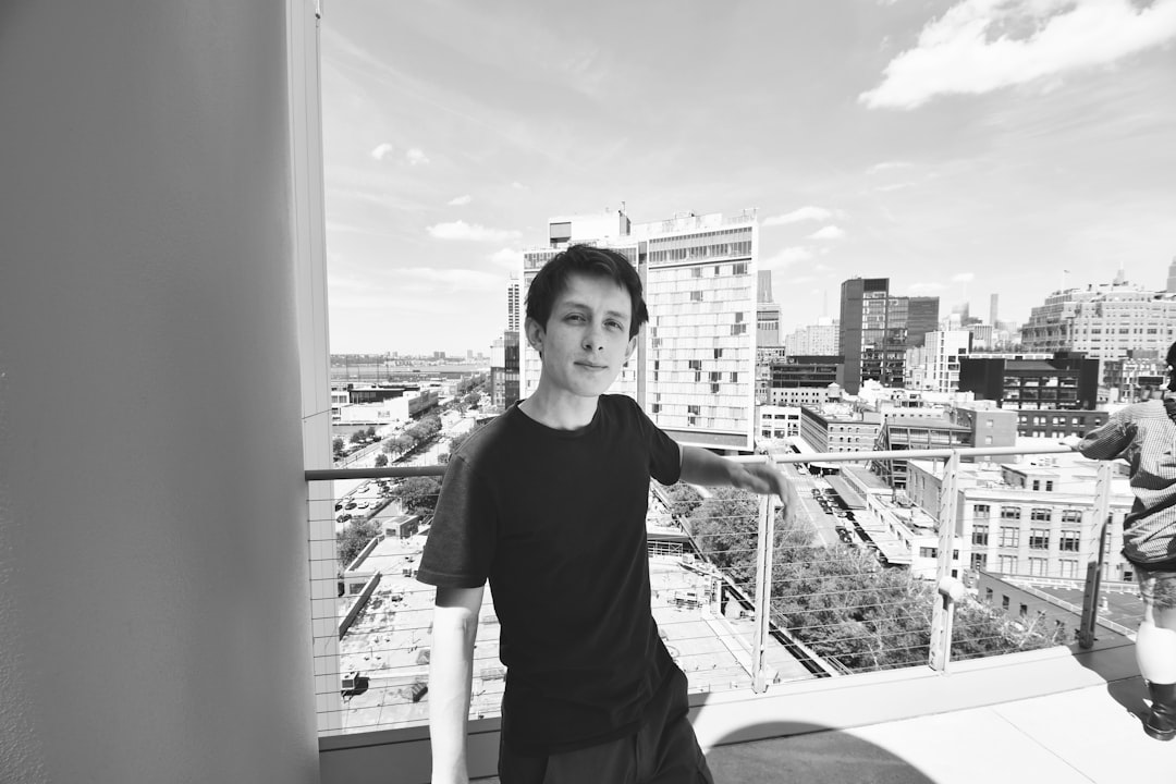 grayscale photo of woman in black crew neck t-shirt standing on balcony