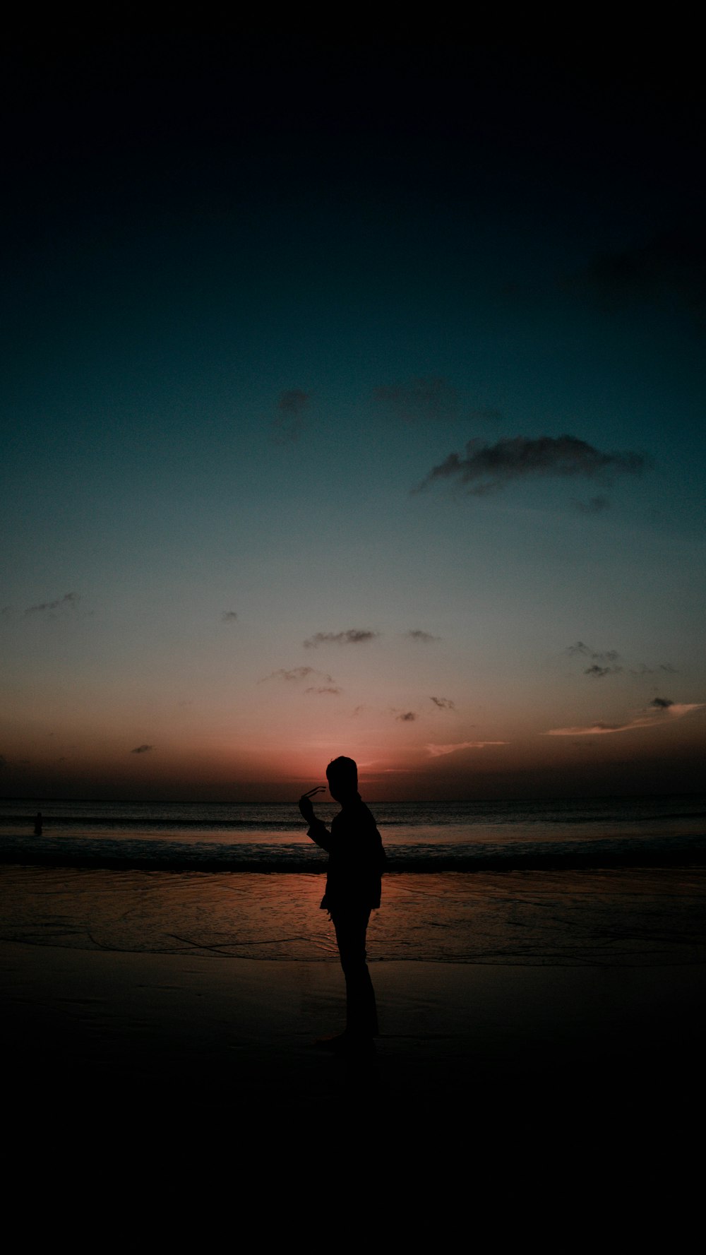 夕暮れ時の浜辺に立つ人のシルエット
