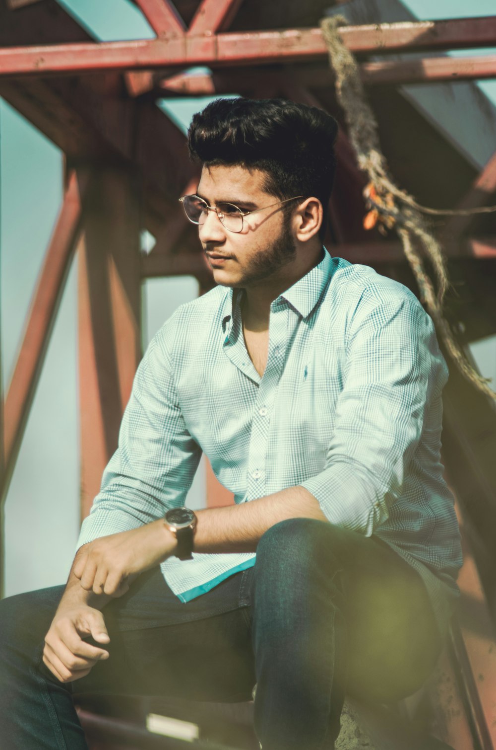 man in white dress shirt and green pants sitting on brown wooden bench