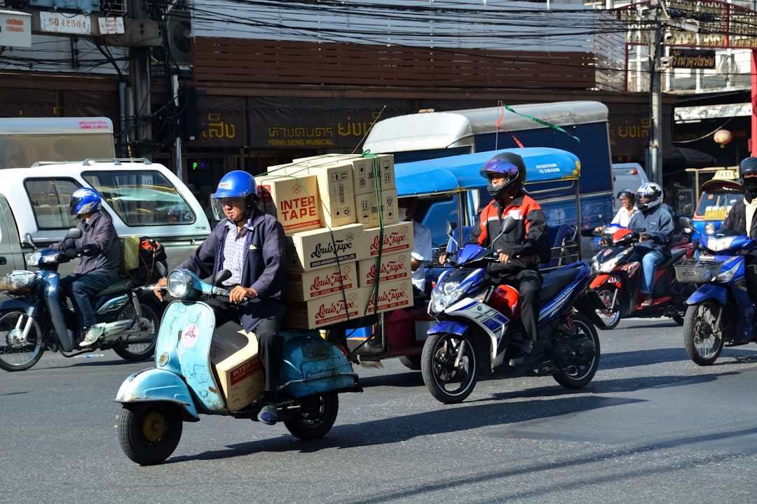2 men riding on blue and white motor scooter during daytime