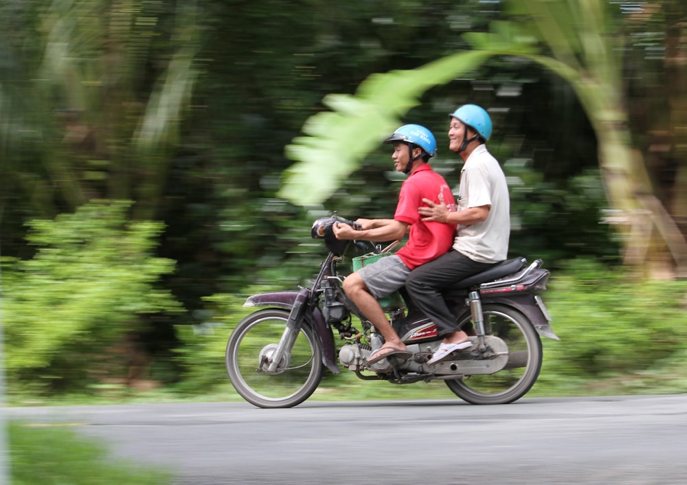 2 men riding motorcycle on road during daytime