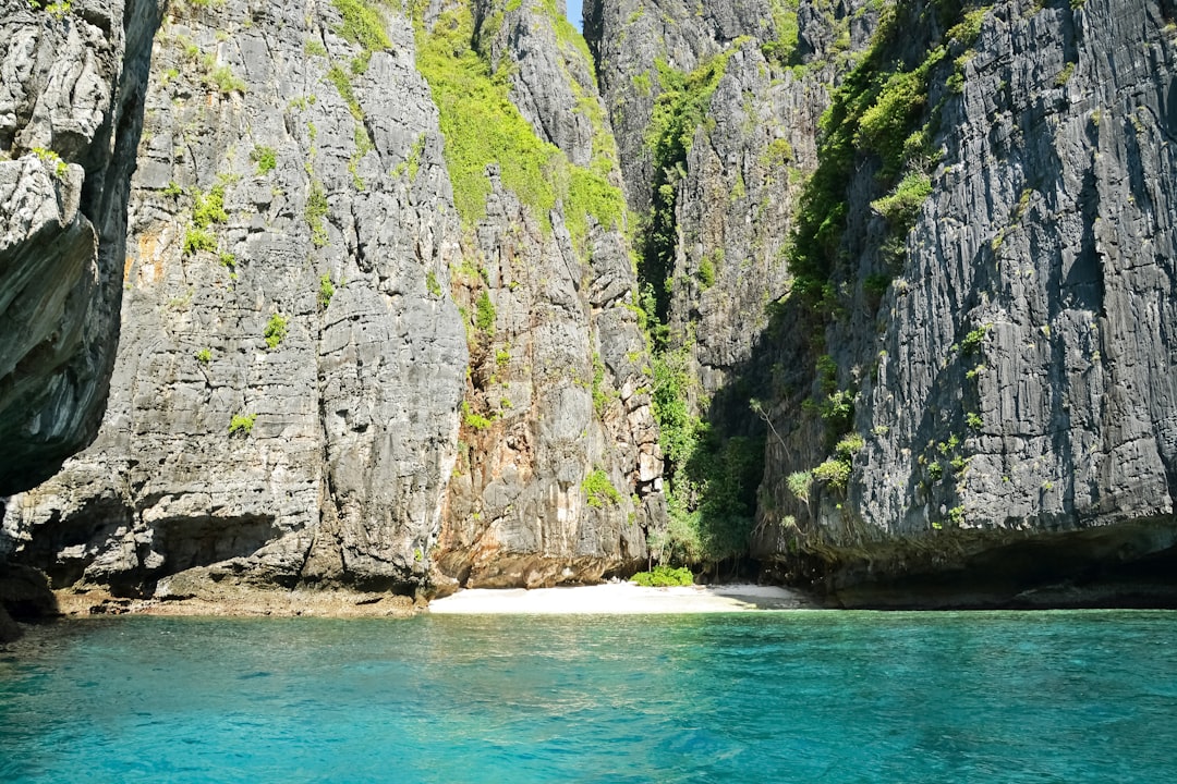 gray rocky mountain beside blue sea during daytime