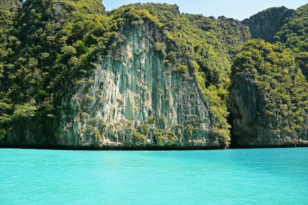 green and brown mountain beside blue sea during daytime