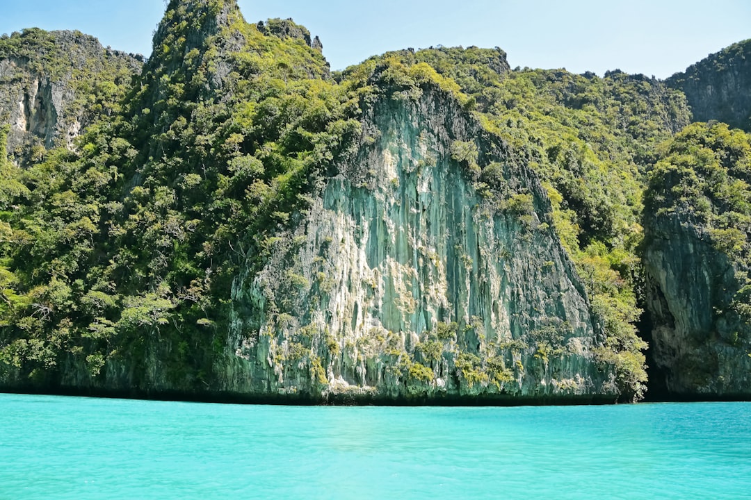 green and brown mountain beside body of water during daytime