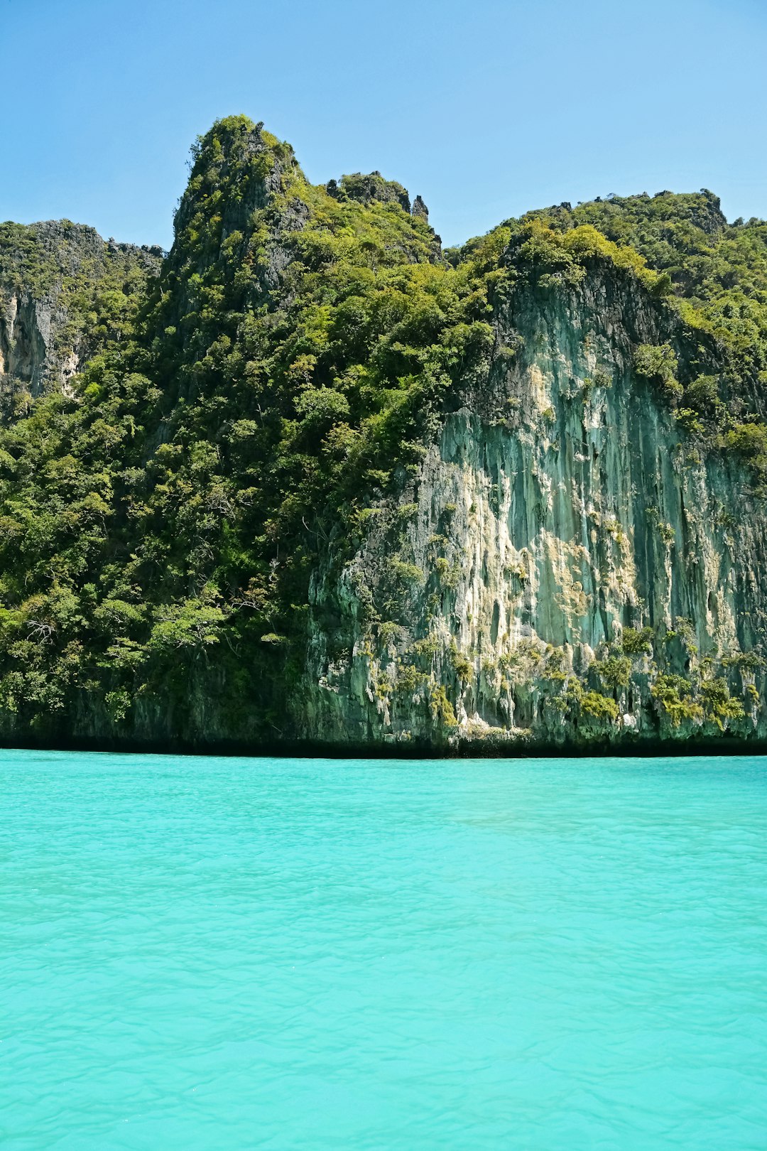 green and brown mountain beside blue sea during daytime