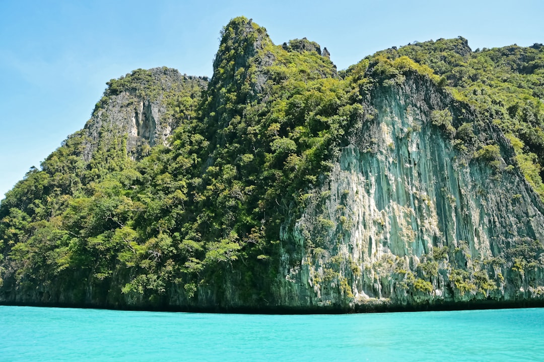 green and brown mountain beside body of water during daytime