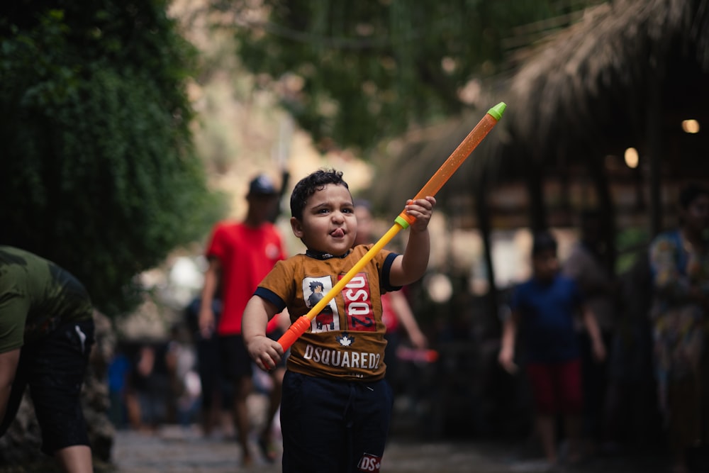 boy in red and white crew neck t-shirt holding brown stick