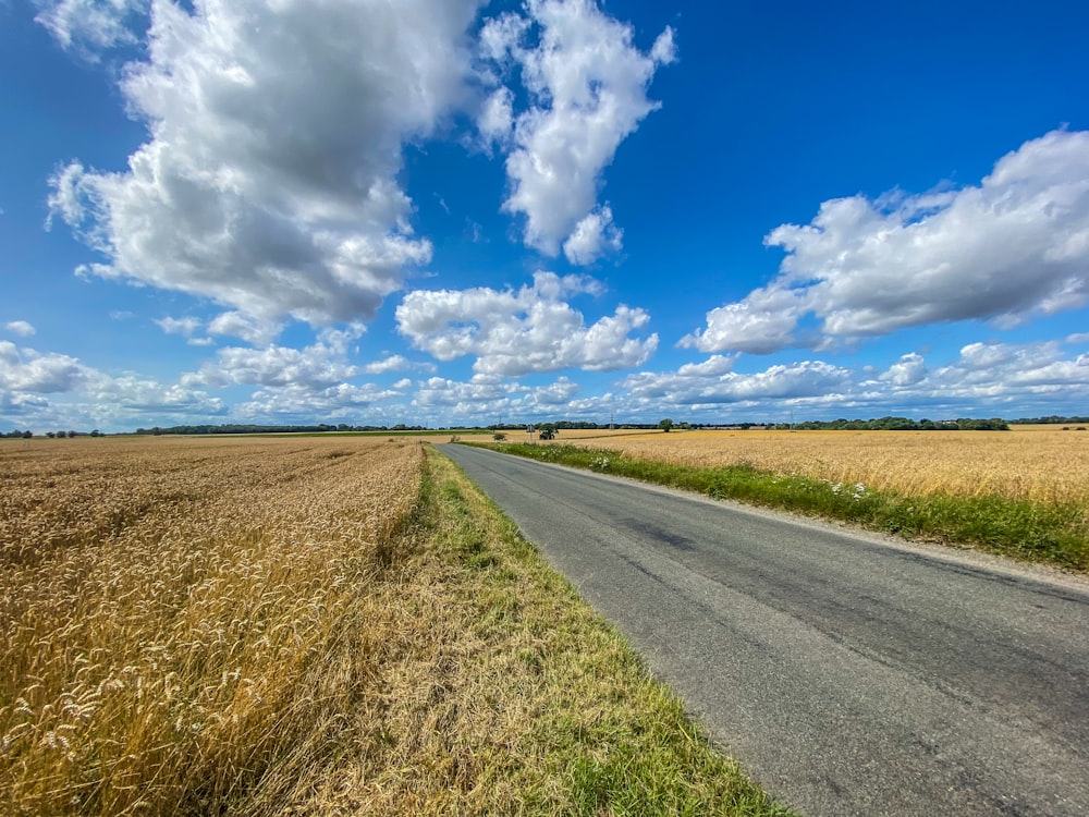 gray asphalt road under blue and white cloudy sky during daytime