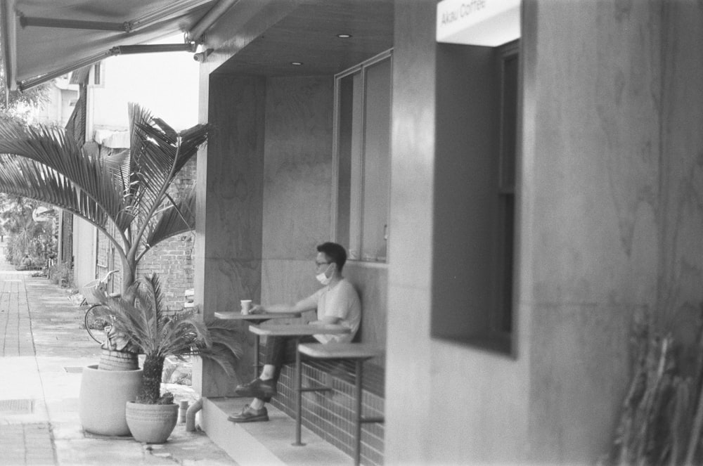 grayscale photo of man sitting on chair