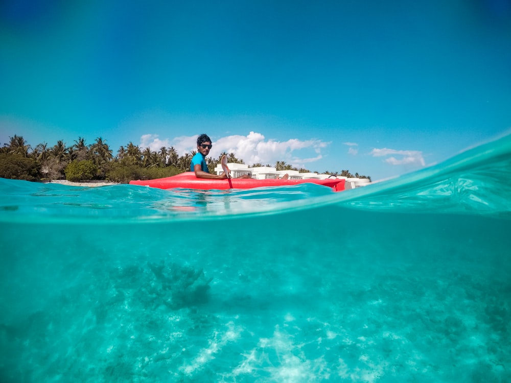 femme en haut de bikini noir et rose équitation planche de surf blanche et rouge sur la mer bleue pendant