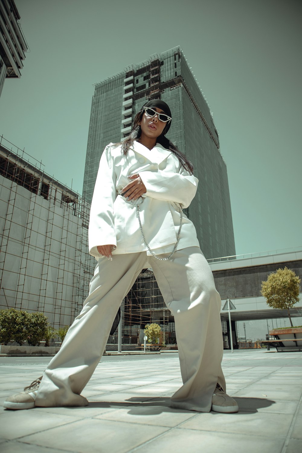 Mujer con camisa blanca de manga larga y pantalones blancos de pie cerca de un edificio blanco durante el día