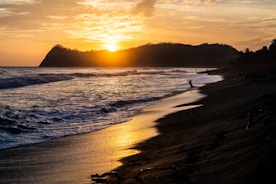 silhouette of person surfing on sea during sunset