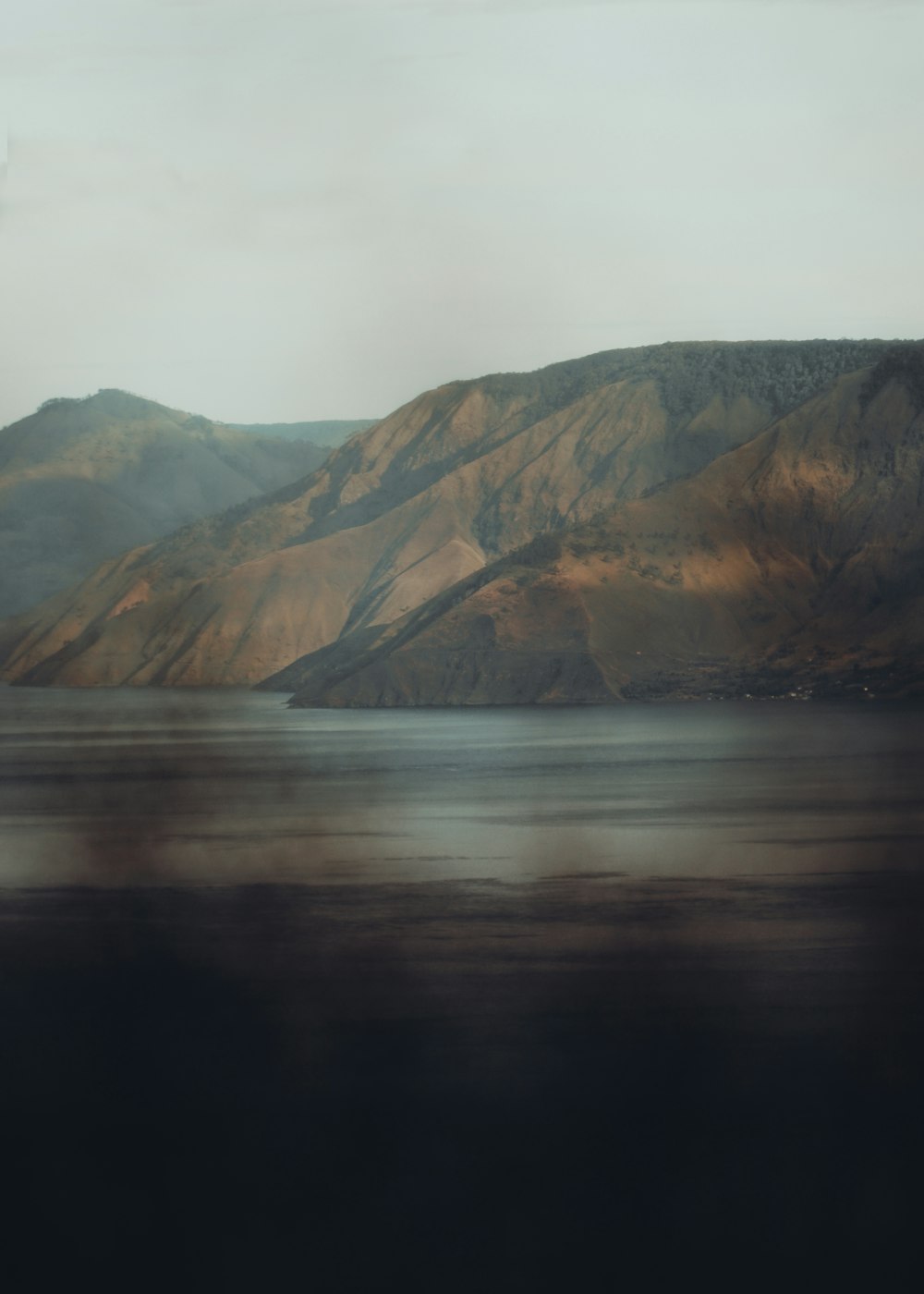 brown and green mountains beside body of water during daytime