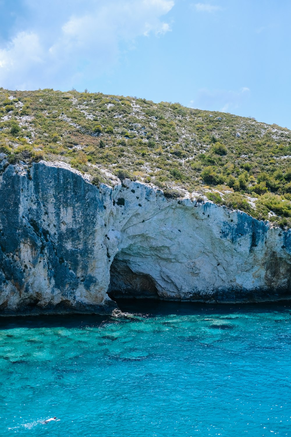 gray and green rock formation on blue sea under blue sky during daytime