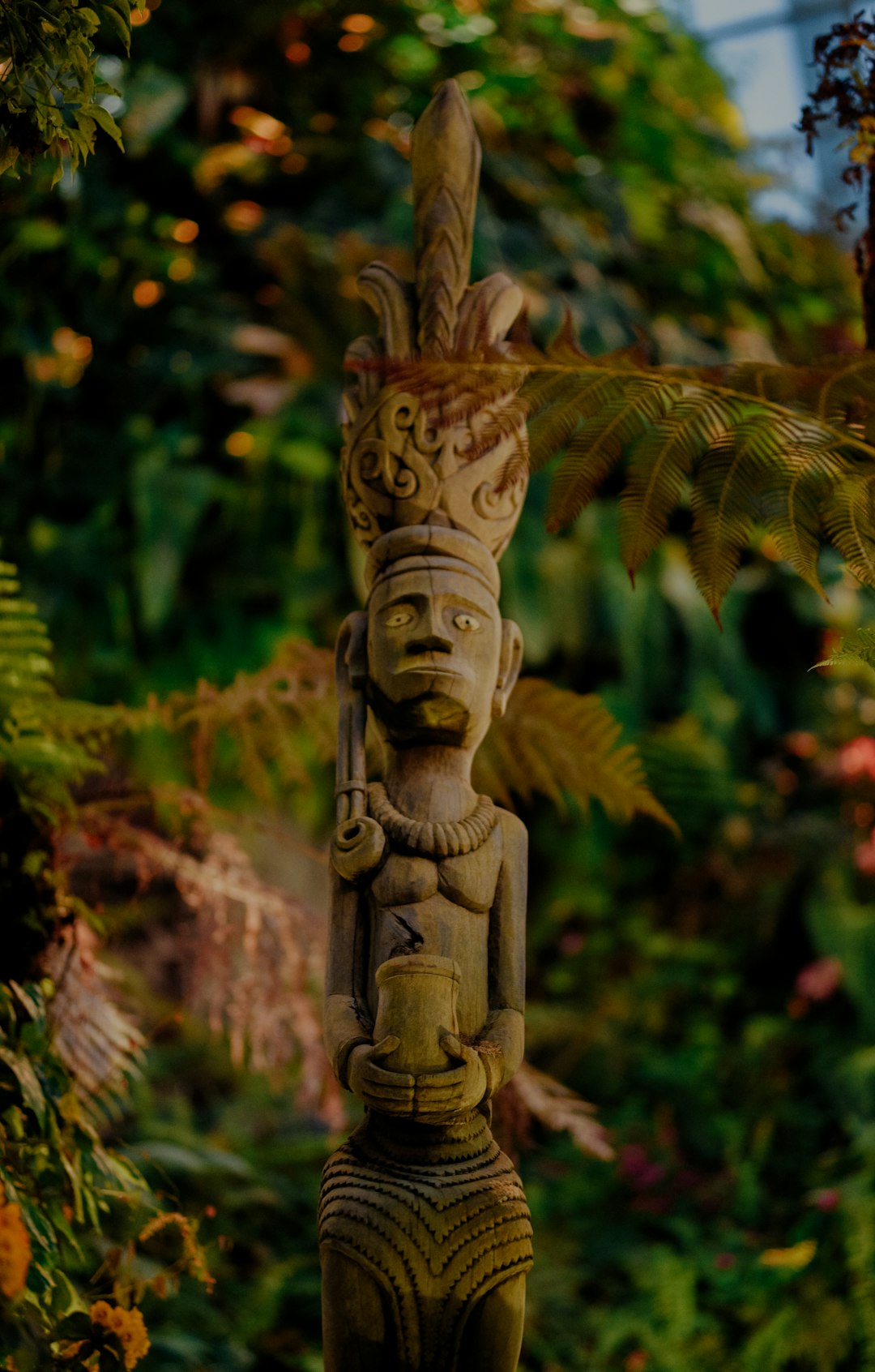 brown wooden statue near green plants during daytime