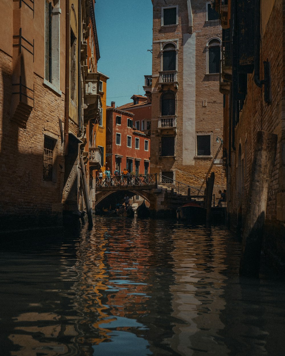 brown boat on river between brown concrete buildings during daytime