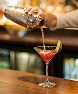A vibrant cocktail being poured into a glass at an elegant event.