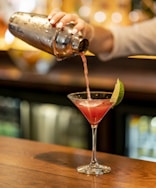 person pouring beverage on clear drinking glass