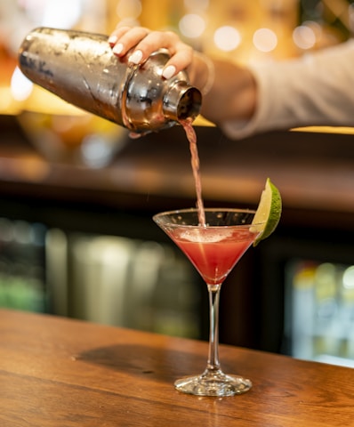 person pouring beverage on clear drinking glass