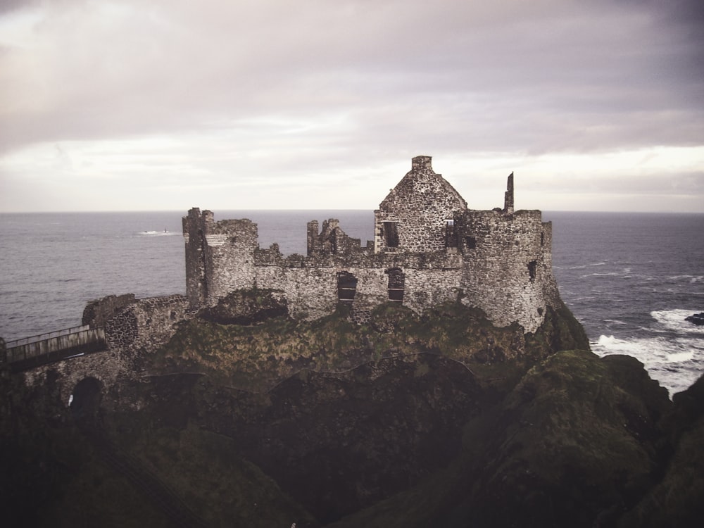 brown concrete castle on top of mountain near body of water during daytime