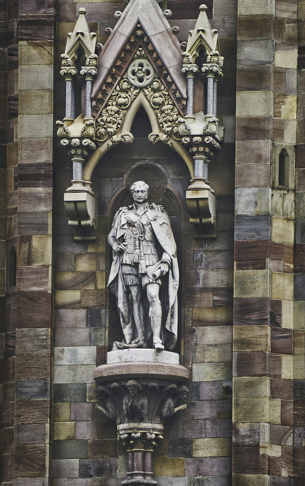 Mann im Gewand Statue an brauner Ziegelmauer