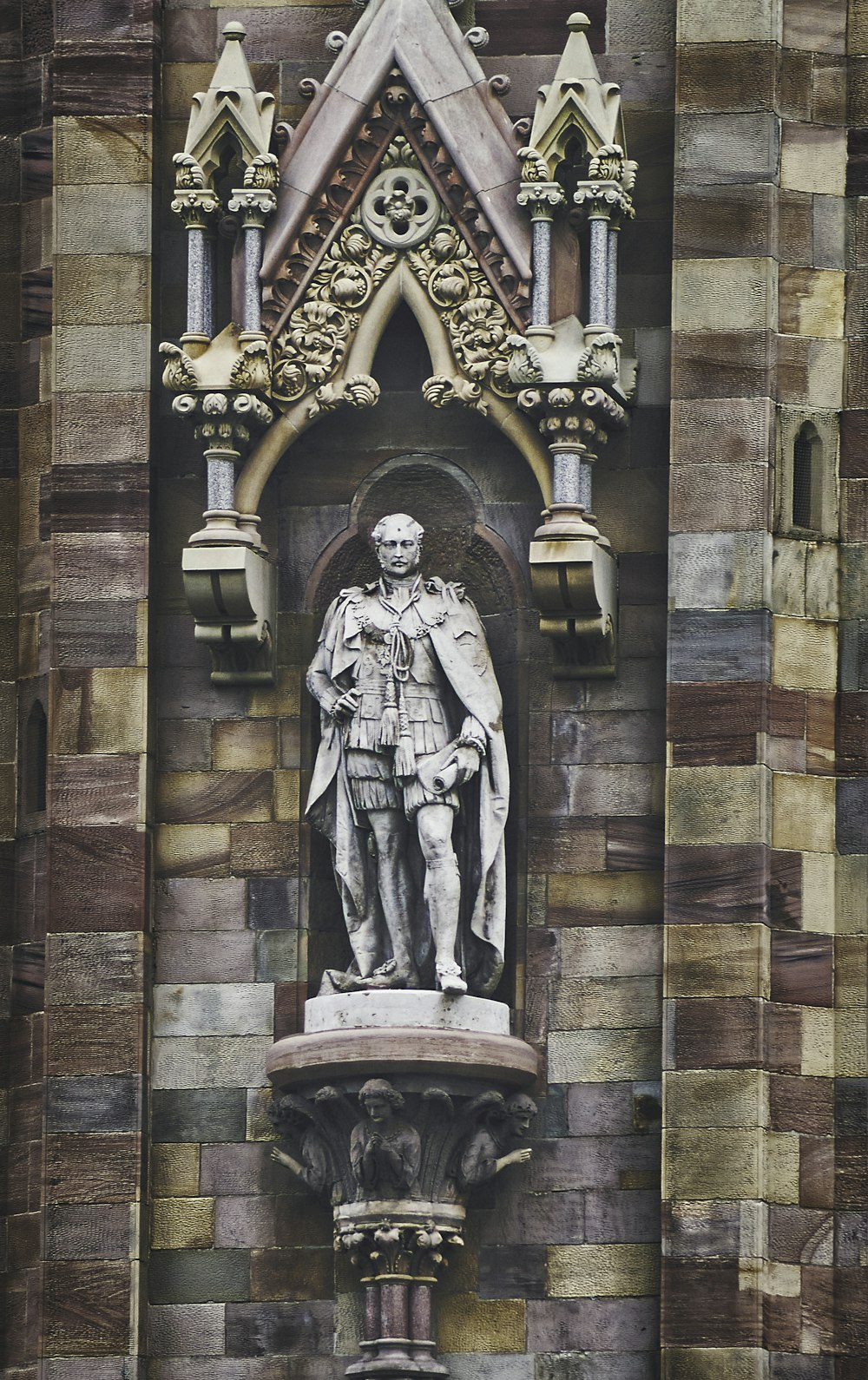 Hombre en túnica estatua en pared de ladrillo marrón