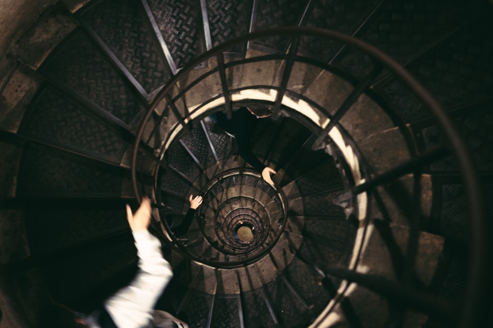 person in white long sleeve shirt and white pants walking on spiral staircase