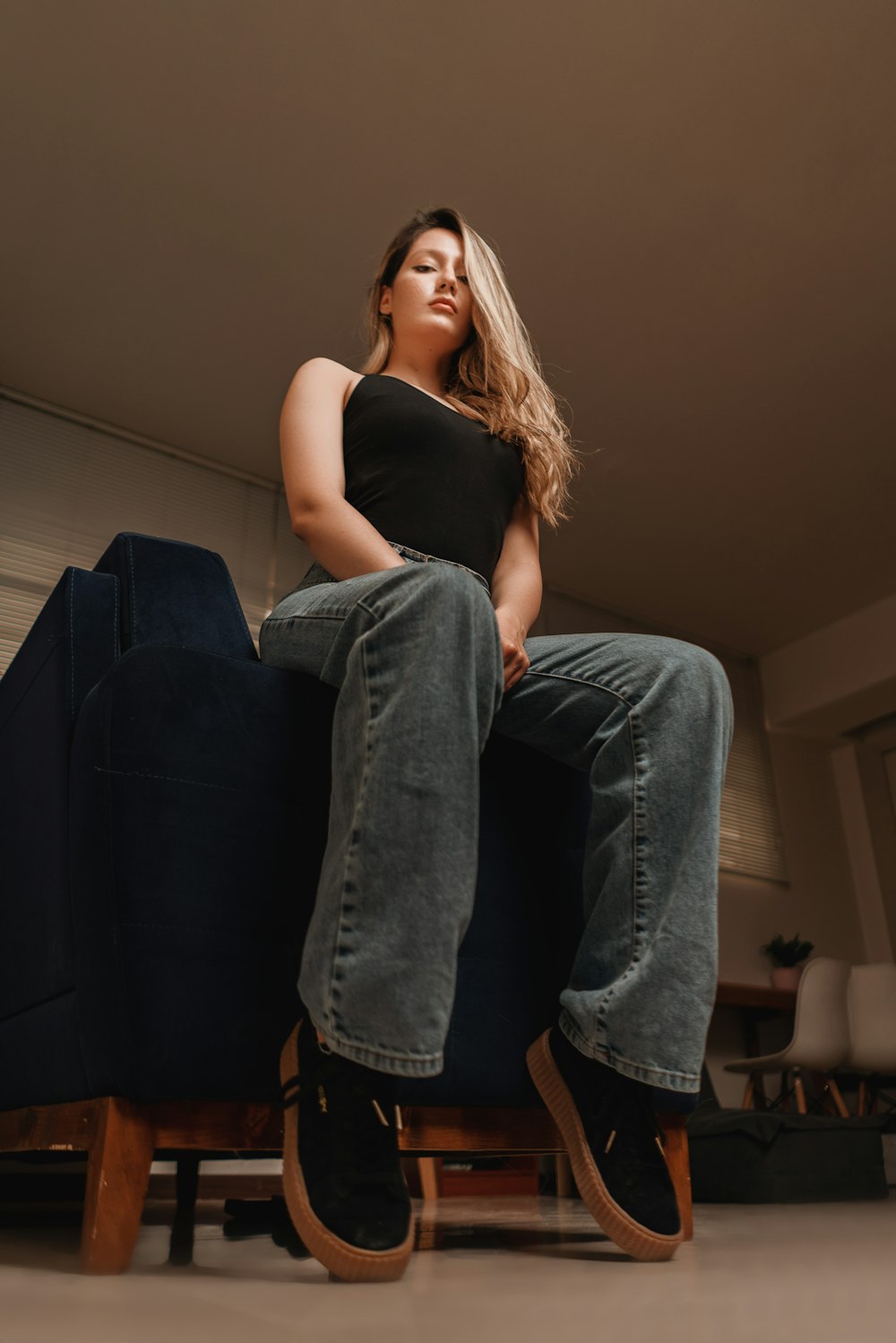 woman in black tank top and blue denim jeans sitting on black sofa