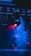 Stage lighting equipment emits vibrant beams of red and blue light, surrounded by a haze that enhances the dramatic effect. The setup includes overhead structures and cables, typical of a professional lighting rig.
