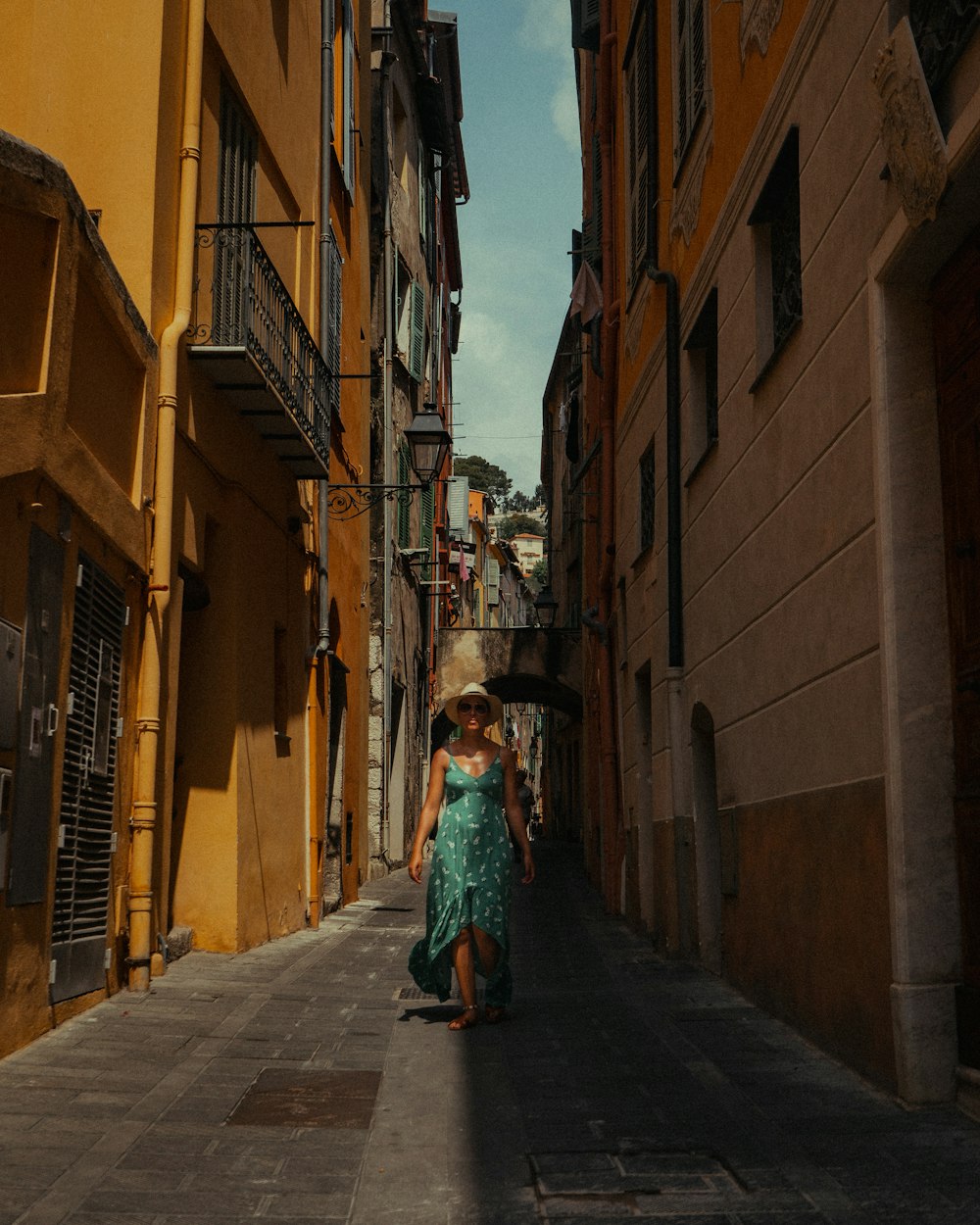 woman in green dress walking on street during daytime