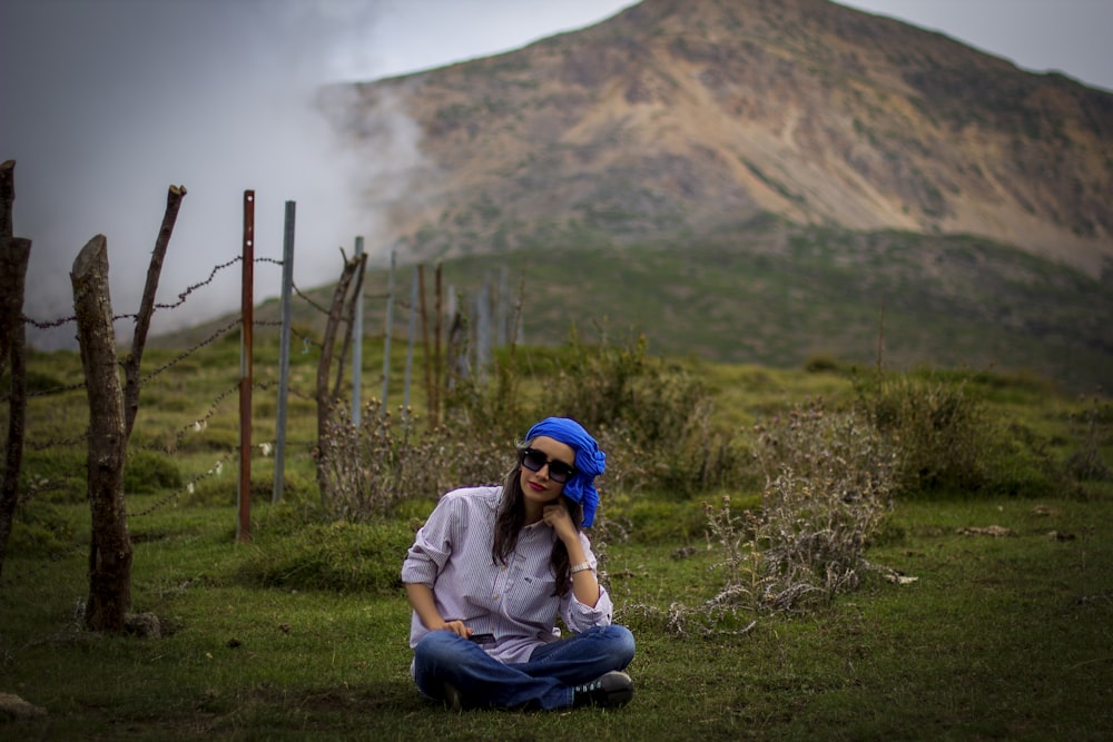 woman in white shirt and blue pants sitting on green grass field