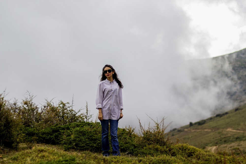 woman in white long sleeve shirt and blue denim jeans standing on green grass field