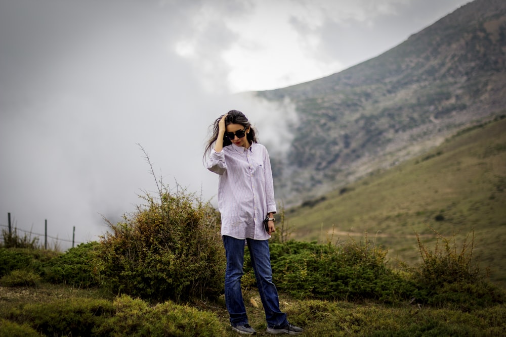 woman in white hoodie standing on green grass field during daytime