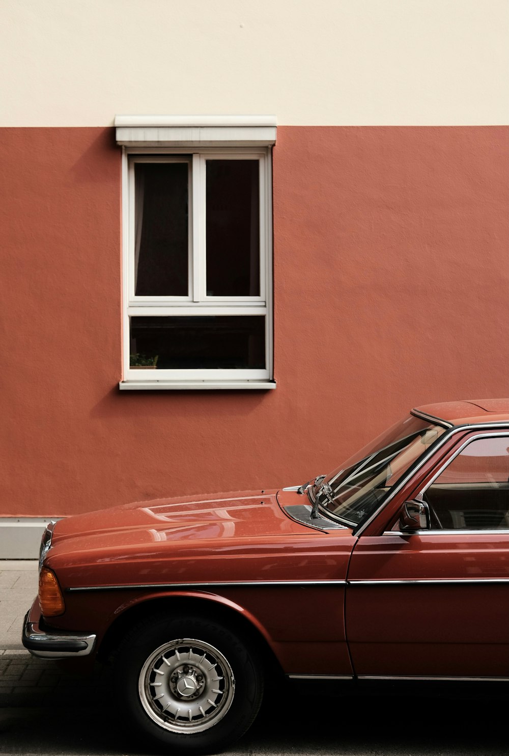 red car parked beside brown concrete building