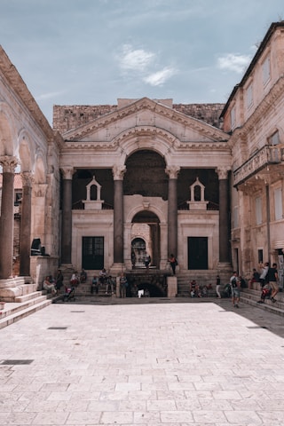 people sitting on bench in front of brown concrete building during daytime